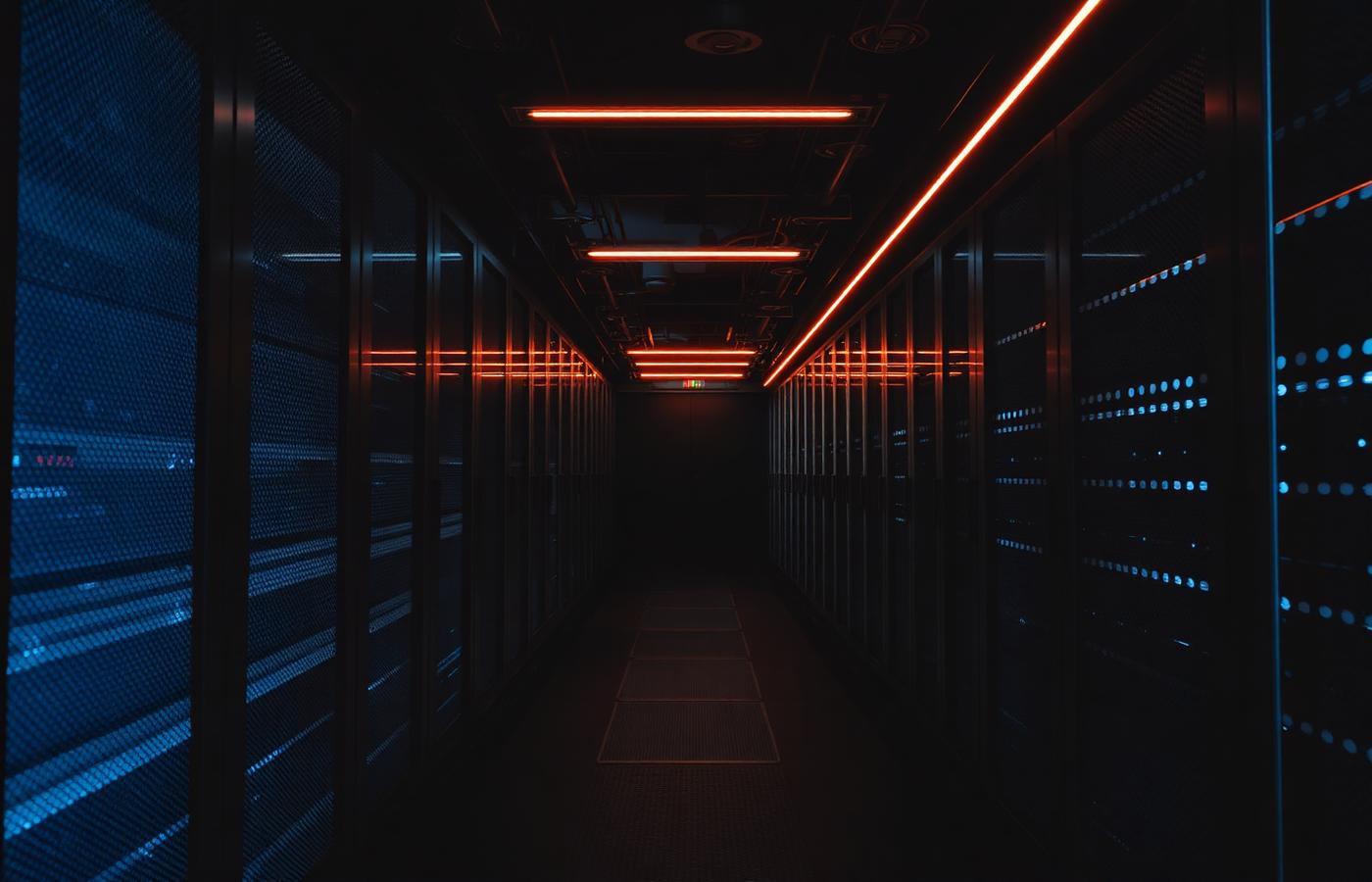 Dark server room corridor with illuminated racks, representing production technology infrastructure
